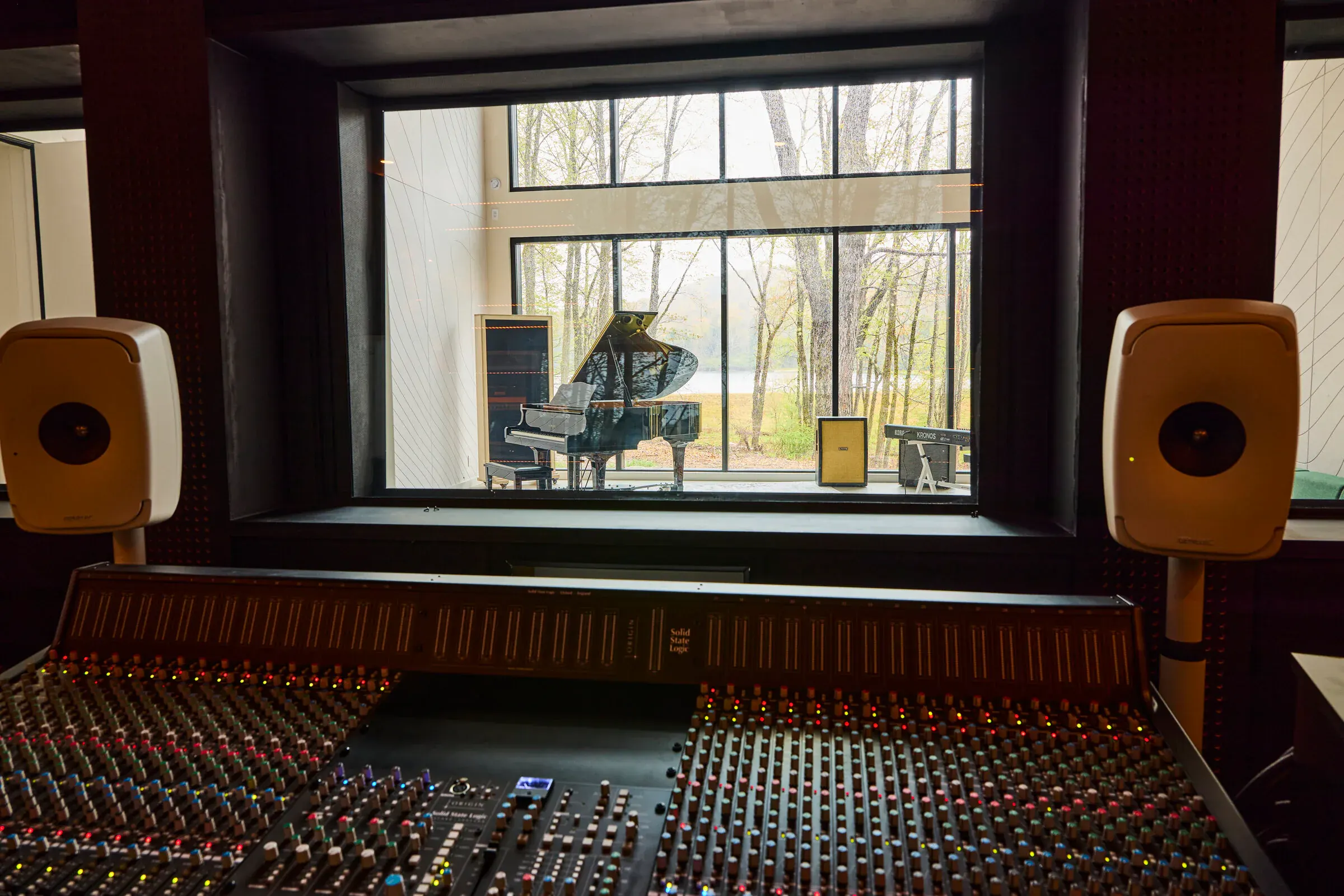 View from the Verdant Sound control room through the isolation glass into the live room — grand piano and lake